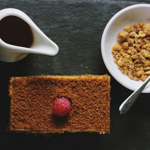 Flat lay of breakfast cake, syrup, and hazelnuts