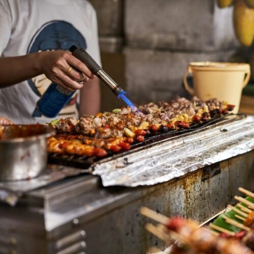 a person cooking food on a grill with tongs