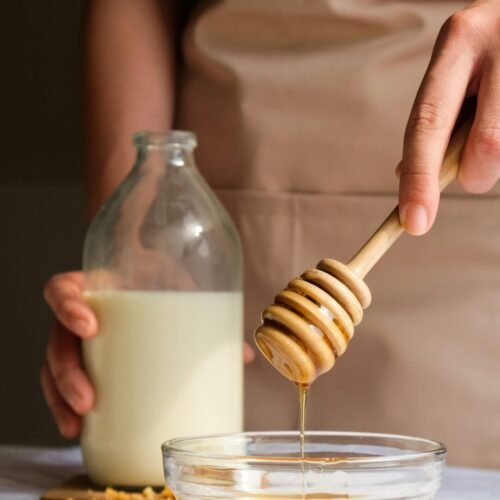 person holding clear glass jar with white liquid