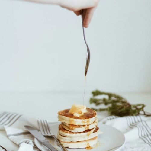 person pouring honey on top of pancake