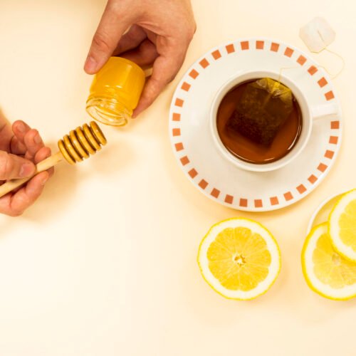 person-s-hand-peaking-honey-from-jar-healthy-tea